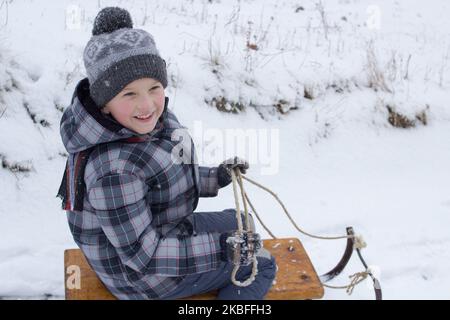 Little boy enjoying a sleigh ride. Child sledding. Toddler kid riding a sledge. Children play outdoors in snow. Kids sled in mountains in winter. Outd Stock Photo