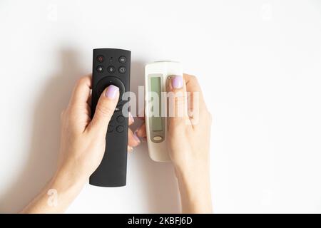 Two remote controls in female hands on a white background close-up, TV remote control Stock Photo