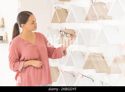 Optometry, vision and woman choosing glasses in retail optical store for eye health, wellness and care. Optician, spectacles and lady customer picking Stock Photo