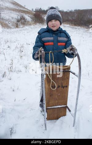 The boy in a cold winter day, a walk in the Park, holding the sled .Winter active holiday Stock Photo