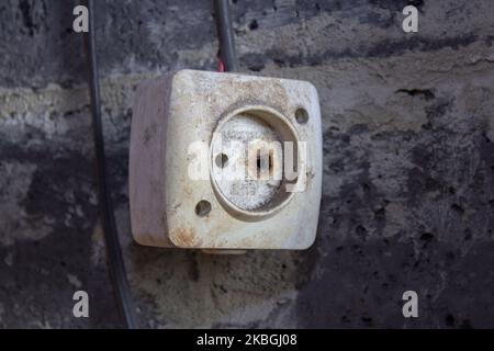 old dangerous electrical outlet on the wall hangs dirty Stock Photo