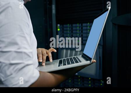 Modern tools for a modern IT technician. an IT technician using a laptop while working in a data center. Stock Photo