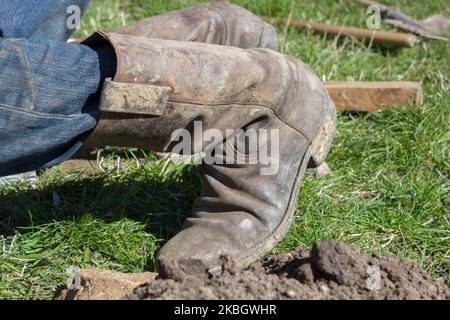kneeling in the old high boots on grass Stock Photo