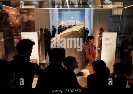 Visitors view the Rosetta Stone in the ancient Egypt section of the British Museum in London, England, on February 13, 2020. The museum, one of London's top tourist attractions, is rarely far from controversy, from its long-running refusal to comply with Greek wishes for repatriation of the Parthenon Sculptures (otherwise known as the Parthenon or Elgin Marbles), to other debates on restitution over artifacts including the Rosetta Stone (taken from Egypt) and Benin bronzes (taken from what is now Nigeria), to more recent pressure from climate activists over the institution's sponsorship ties t Stock Photo