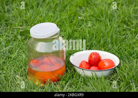 Canned tomatoes on the grass in a bowl and jar Stock Photo