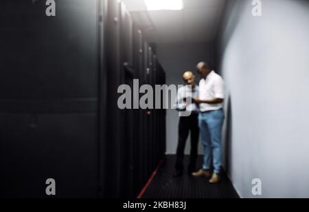 Essential equipment. Full length shot of two IT technicians using a digital tablet while working in a data center. Stock Photo