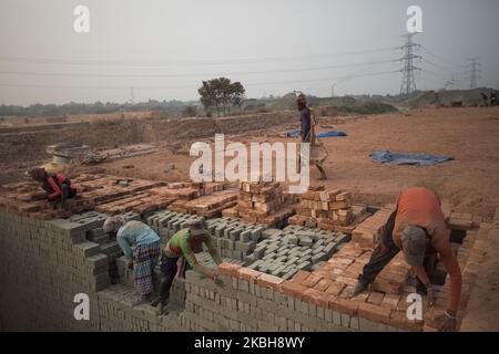 Workers are working in Brickfield in Savar on February 19, 2020. The world is going through a speedy urbanization and Bangladesh is not an exception from this. Such rapid urbanization generates a massive demand for bricks as it is one of the key ingredients to build concrete structure. To meet this growing need, numbers of brick making field have been increasing at an alarming rate in Bangladesh. Most of them took place in farming lands which causes reduction of agricultural production. We know that burning coal causes tremendous emission of Carbon-Di-Oxide (CO2) gas which is primarily respons Stock Photo