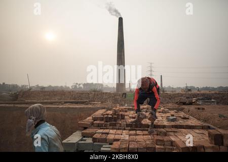 Workers are working in Brickfield in Savar on February 19, 2020. The world is going through a speedy urbanization and Bangladesh is not an exception from this. Such rapid urbanization generates a massive demand for bricks as it is one of the key ingredients to build concrete structure. To meet this growing need, numbers of brick making field have been increasing at an alarming rate in Bangladesh. Most of them took place in farming lands which causes reduction of agricultural production. We know that burning coal causes tremendous emission of Carbon-Di-Oxide (CO2) gas which is primarily respons Stock Photo