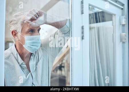 Lonely, face mask and senior man in the house for quarantine, protection and isolation during pandemic. Depression, frustrated and sad elderly guy Stock Photo
