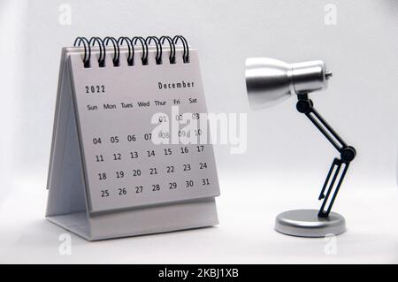 December 2022 white desk calendar on white background with table lamp. Calendar concept. Stock Photo