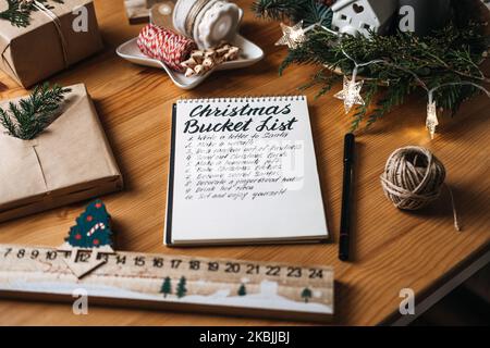 Christmas bucket list, countdown to Xmas checklist. Tasks you need to do in preparation for winter holidays. Woman writes in a notebook to do list for Stock Photo