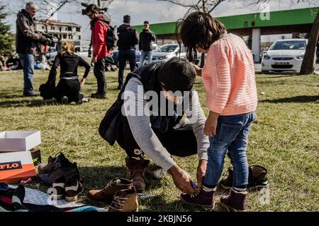 Father put new shoes to his child which was given them by people from Edirne as donation. Many children suffer because of the migrants crisis along Turkey-Greece border. There are many families with kids trying to start a new life somewhere in the EU. For now, they are stranded in parking lots, on bus stations in Edirne, or even in the no man's land between Pazarkule and Kastanies, Edirne, Turkey on March 9, 2020 (Photo by Hristo Rusev/NurPhoto) Stock Photo