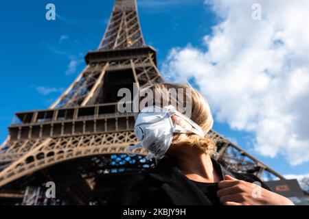 A woman with a face mask in front the Eiffel tower in Paris, France, on March 13, 2020. The day after the President 's intervention on Television about Coronavirus,in Paris, there is no traffic on the usual busy streets, busy places,as place de la Concorde,which was almost empty of cars, of people.Parisians are starting to wear face mask,as the tourists do ,in tourist places, on the streets, in subway, even in their car.some Museum are starting to close as the orsay museum, the louvre museum was quiet as ever. (Photo by Jerome Gilles/NurPhoto) Stock Photo