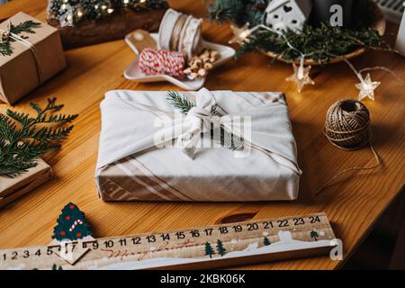Christmas Furoshiki Japanese Fabric Wrapping gifts. Xmas Zero waste reusable eco friendly sustainable Christmas gift wrapping in linen fabric on table Stock Photo