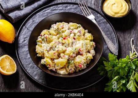shout hallelujah potato salad with pickles, celery, eggs, jalapeno and mayonnaise dressing in black bowl, close-up Stock Photo