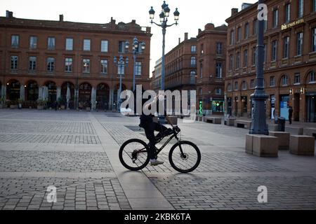 A dispatch rider with a face mask makes the V sign on the Capitole square. For the 2nd day, French people are on lockdown. On Monday March 16th, French President Macron announced that all people will be on lockdown due to the Covid-19 coronavirus pandemic. In Toulouse as elsewhere in France, all shops 'non essentials' were closed until further notice. Police patrols the streets to check people outside. People must have a permit to move around. As the Covid-19 coronavirus spreads across France, President Macron announced the closing down of all schools, highchools, universities to try to contai Stock Photo