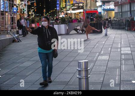 A woman takes a photo of a breakdancer in Times Square on Friday, March 2020 in New York, NY. The city officially announced the closure of all non-essential businesses and implemented a lockdown order earlier in the week. (Photo by Erin Lefevre/NurPhoto) Stock Photo