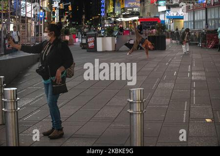 A woman takes a photo of a breakdancer in Times Square on Friday, March 2020 in New York, NY. The city officially announced the closure of all non-essential businesses and implemented a lockdown order earlier in the week. (Photo by Erin Lefevre/NurPhoto) Stock Photo