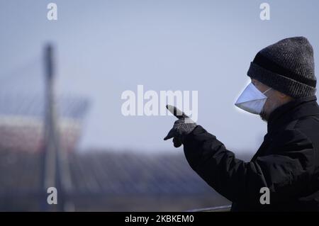 A man wearing a surgical mask is seen with the National Stadium in the backgroun in Warsaw, Poland on March 23, 2020. Polish government spokesman Piotr Muler on Monday announced the administration would not rule out further expanding restrictions to prevent the spread of the coronavirus. The government in the previous week already banned the opening of cinemas, restaurants and bars for at least ten days. People are encouraged to stay at home and gatherings of more than 50 people are prohibited. (Photo by Jaap Arriens/NurPhoto) Stock Photo
