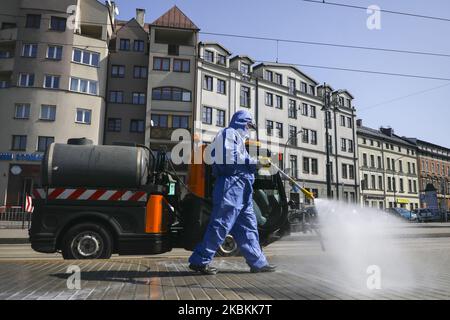 A worker of Municipal Cleaning Company (MPO) uses a pressure hose to disinfect bus and tram stop as well as public squares with cleaning agents against the spread of coronavirus. Krakow, Poland on March 27, 2020. Poland's government decided to introduce new limitations across the country, such as rules preventing leaving home unless justified. (Photo by Beata Zawrzel/NurPhoto) Stock Photo