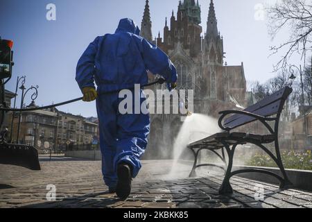 A worker of Municipal Cleaning Company (MPO) uses a pressure hose to disinfect bus and tram stop as well as public squares with cleaning agents against the spread of coronavirus. Krakow, Poland on March 27, 2020. Poland's government decided to introduce new limitations across the country, such as rules preventing leaving home unless justified. (Photo by Beata Zawrzel/NurPhoto) Stock Photo