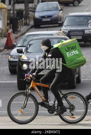 A courier with Uber Eats bag rides a bicycle in Kyiv, Ukraine, on 27 March, 2020. To stem the spread of the coronavirus COVID-19 the Ukrain's Cabinet of Ministers has introduced a 30-day emergency situation regime in the entire territory of Ukraine until April 24, 2020. (Photo by STR/NurPhoto) Stock Photo