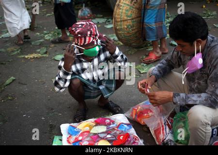 A man trials a face mask from a street vendor at Kawran Bazar whole sale market in Dhaka, Bangladesh on Sunday, Mar. 29, 2020. (Photo by Syed Mahamudur Rahman/NurPhoto) Stock Photo