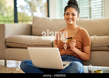 Paying online with no queues makes one happy shopper. a beautiful young woman using a laptop and credit card at home. Stock Photo