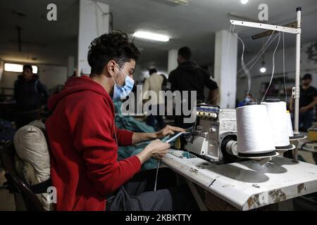 A palestinian worker manufacture protective coverall suits and masks at a workshop in Gaza City on March 31, 2020. amid coronavirus COVID-19 pandemic. Factories in the Gaza Strip used to specialize in the manufacture of shirts and jeans, for despite the closure of many of them in previous years due to the blockade imposed on the Gaza Strip and the inability to export and its aftermath From economic problems that led to the closure of many factories, But with the invasion of the new coronavirus to the world, some factories returned to work in medical clothing, and lines of men and women used ol Stock Photo