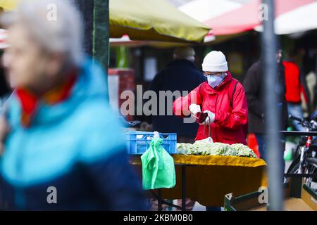 A woman wears a protective face mask due to the spread of coronavirus while doing shopping at the outdoor marketplace in Krakow, Poland on April 4th, 2020. Poland's government introduced tough new restrictions battling COVID-19 infections, such as preventing leaving home unless justified, banning children under 18 from leaving home unless supervised by an adult, closing access to parks, boulevards, squares and wearing gloves on while shopping. (Photo by Beata Zawrzel/NurPhoto) Stock Photo