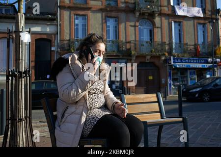 A woman with a face mask makes a call to have an appointment with a doctor on a public place in Toulouse, France, on April 4, 2020. The lockdown due to the Covid-19 massive outbreak are extended until April 15th. Police patrols the streets to check if people have the mandatory laissez-passer to move around. There is fewer people in the streets than other days as stay-at-home directives are enforced. Since March 16th when French President Macron announced that all people will be on lockdown due to the Covid-19 coronavirus pandemic, all shops 'non essentials' are closed until further notice exce Stock Photo