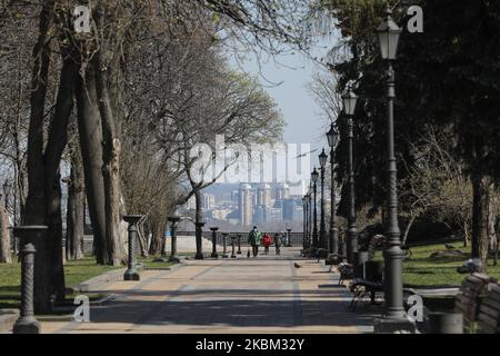 People walk through the deserted park in Kyiv, Ukraine, April 6, 2020. Ukraine's Government has toughened the restrictive quarantine measures to prevent the spread of COVID-19 in Ukraine since 06, March. People are obliged to wear a mask or a respirator in all public places, meetings of a group of more than two people are banned, as well as visiting parks, public gardens, recreation areas, etc. Citizens must carry identification documents to check whether a person should be on self-isolation or in observation. (Photo by Sergii Kharchenko/NurPhoto) Stock Photo