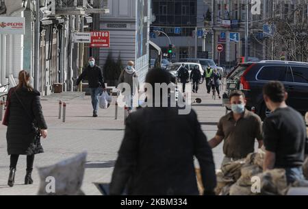 People with the face masks on walk through the Independence Square in Kyiv, Ukraine, April 6, 2020. Ukraine's Government has toughened the restrictive quarantine measures to prevent the spread of COVID-19 in Ukraine since 06, March. People are obliged to wear a mask or a respirator in all public places, meetings of a group of more than two people are banned, as well as visiting parks, public gardens, recreation areas, etc. Citizens must carry identification documents to check whether a person should be on self-isolation or in observation. (Photo by Sergii Kharchenko/NurPhoto) Stock Photo