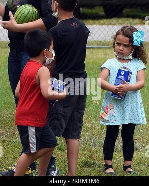 Children wearing protective face masks hold food assistance from the Second Harvest Food Bank of Central Florida at a mobile food drop event at the Impact Outreach Ministry on April 6, 2020 in Orlando, Florida, US. While donations are down, many food banks across the country are scrambling to keep up with a skyrocketing demand for food due to job losses as businesses furlough workers due to the COVID-19 pandemic. (Photo by Paul Hennessy/NurPhoto) Stock Photo