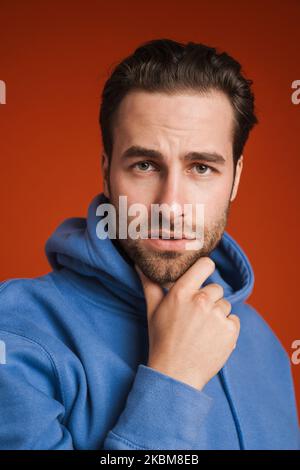 Young white man wearing hoodie posing and looking at camera isolated over red background Stock Photo