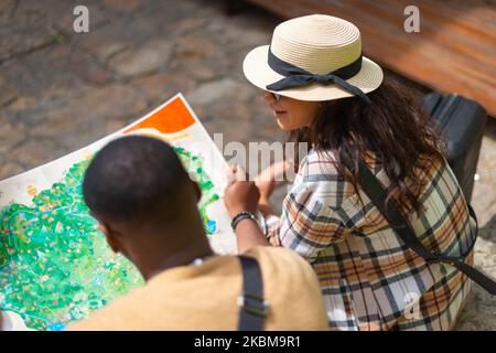 A cool multiethnic couple is sitting and talking, outdoors Stock Photo
