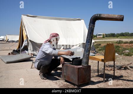 A Syrian protestor makes tea near his tent on the M4 highway near the village of al-Nayrab, where dozens of Syrians protest against joint Turkish-Russian military patrols on M4 highway, which links the northern Syrian provinces of Aleppo and Latakia. On April 14, 2020. (Photo by Karam Almasri/NurPhoto) Stock Photo