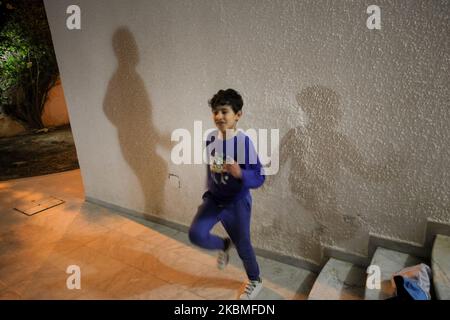 A teenager plays sport as his father's shadow is cast behind him on a wall, at night in the backyard of their house and during the curfew imposed by the president of Tunisia, Kais Saied, in Ariana governorate, Northern Tunisia, as they try to chase away the vacuity, the stress and to stay in shape during the general lockdown imposed by the Tunisian authorities in bid to slow down the spread of the novel coronavirus outbreak that causes the Covid-19 disease in Tunisia, on April 06, 2020. (Photo by Chedly Ben Ibrahim/NurPhoto) Stock Photo