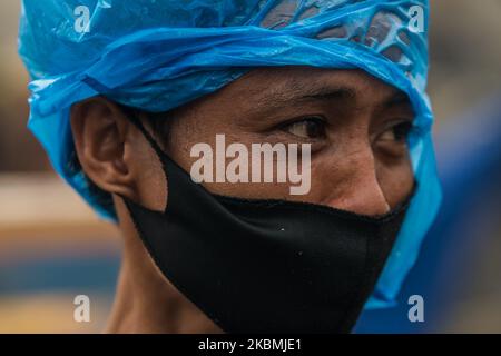 A man wearing a protective face mask covers his head with a plastic in a slum area in Tondo, Manila in the Philippines on April 18, 2020. About 500 families lost their homes after a fire broke out in the area. Manila and the whole of Luzon island remains on enhanced community quarantine. The number of confirmed COVID-19 cases in the country exceeds 6,000.(Photo by Lisa Marie David/NurPhoto) Stock Photo