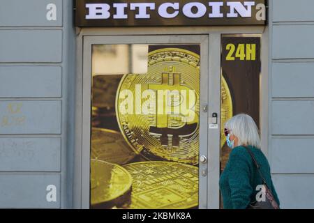 A lady wearing medical masks passes in front of a Bitcoin exchange shop in Krakow's city center. On Saturday, April 18, 2020, in Krakow, Poland. (Photo by Artur Widak/NurPhoto) Stock Photo