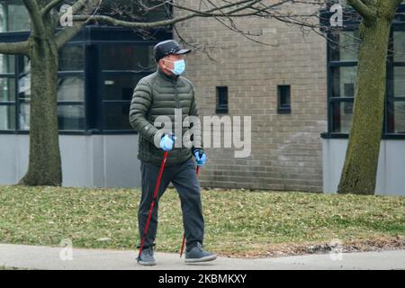 Man wearing a face mask and surgical gloves to protect him from the novel coronavirus (COVID-19) as they walk along the street in Toronto, Ontario, Canada on April 17, 2020. (Photo by Creative Touch Imaging Ltd./NurPhoto) Stock Photo