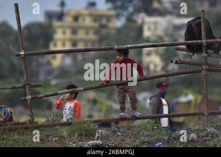 A little kid playing in Iron Fence as his family awaiting local buses managed by local government to travel back home during complete nation lockdown as concerns about the spread of Corona Virus (COVID-19) at Jadibuti, Bhaktapur, Nepal on Wednesday, April 22, 2020. (Photo by Narayan Maharjan/NurPhoto) Stock Photo