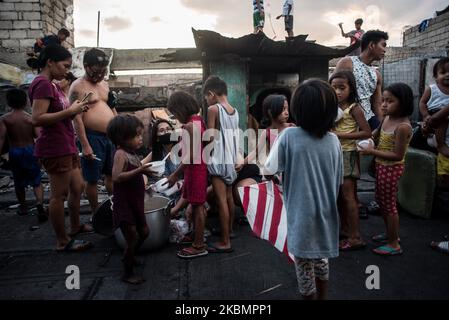 Children line up during a feeding program in Manila, Philippines on April 22, 2020.. On April 18, a fire razed about 500 homes in a slum area in Tondo district in Manila. Many of the fire victims struggle with unemployment as the enhanced community quarantine (ECQ) is still in place in several areas in the Philippines including Manila to curb the spread of COVID-19.(Photo by Lisa Marie David/NurPhoto) Stock Photo