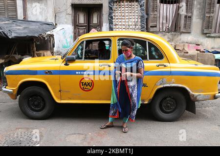 A women wearing protective mask, taking mobile phone at front of yellow ambassador taxi during a government-imposed nationwide lockdown as a preventive measure against the COVID-19 coronavirus, in Kolkata on April 24, 2020. (Photo by Debajyoti Chakraborty/NurPhoto) Stock Photo