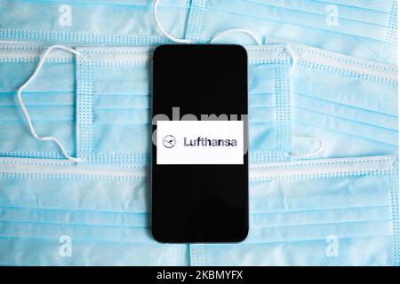 Lufthansa logo is displayed on a mobile phone screen photographed on surgical masks background for illustration photo during the spread of coronavirus. Krakow, Poland on April 26, 2020. (Photo Illustration by Beata Zawrzel/NurPhoto) Stock Photo