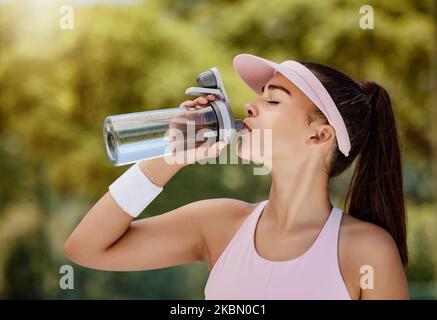 Woman drinking water bottle on break at tennis game, training or workout in summer for hydration. Tennis player girl, drink liquid for health Stock Photo