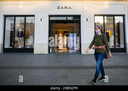 A woman wearing a protective face mask due to the spread of coronavirus is seen outside open Zara shop at the Main Square in Krakow, Poland on April 28, 2020. The rule of covering the nose and mouth in public places with face masks, carves or handkerchiefs came into force from April 16th. The order will not apply to children up to the age of two and people who are unable to cover their mouth or nose due to breathing difficulties. (Photo by Beata Zawrzel/NurPhoto) Stock Photo