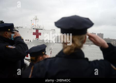 The small New York Police Department pipe and drum band, standing atop an empty parking lot at Pier90, play and salute as the hospital ship USNS Comfort departs New York City during the coronavirus epidemic, Thursday, 30 April 2020. (Photo by B.A. Van Sise/NurPhoto) Stock Photo