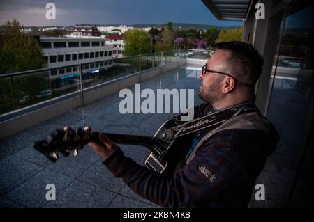 Deyan Stoev rehearses before live streaming. Musicians are organizing secret concerts on balconies in Varna, Bulgaria every Thursday. The musicians self-organized and choose different balconies of apartament buildings around the city to lift the spirits of the neighborhoods during quarantine. They also live stream them on the social medias for the people, Varna, Bulgaria on April 30, 2020 (Photo by Hristo Rusev/NurPhoto) Stock Photo