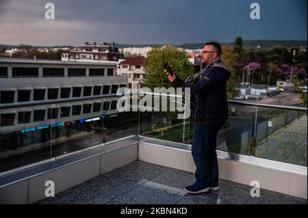 Deyan Stoev rehearses before live streaming. Musicians are organizing secret concerts on balconies in Varna, Bulgaria every Thursday. The musicians self-organized and choose different balconies of apartament buildings around the city to lift the spirits of the neighborhoods during quarantine. They also live stream them on the social medias for the people, Varna, Bulgaria on April 30, 2020 (Photo by Hristo Rusev/NurPhoto) Stock Photo